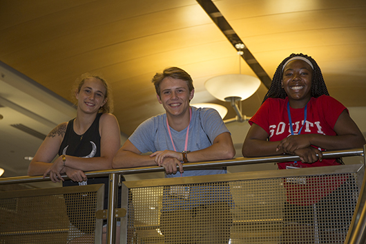 Three students leaning on stair rail.