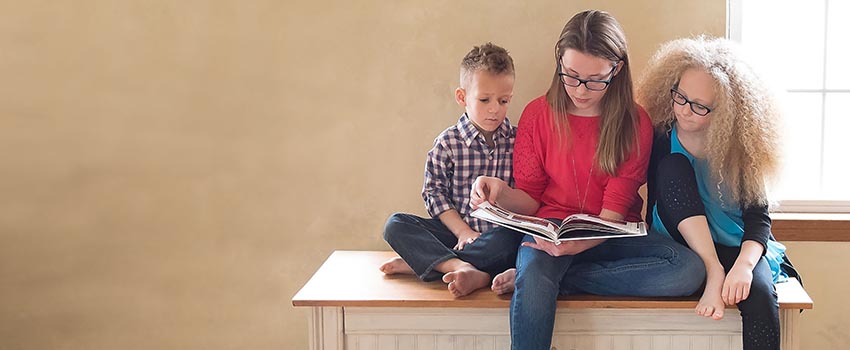 Three kids reading a book.