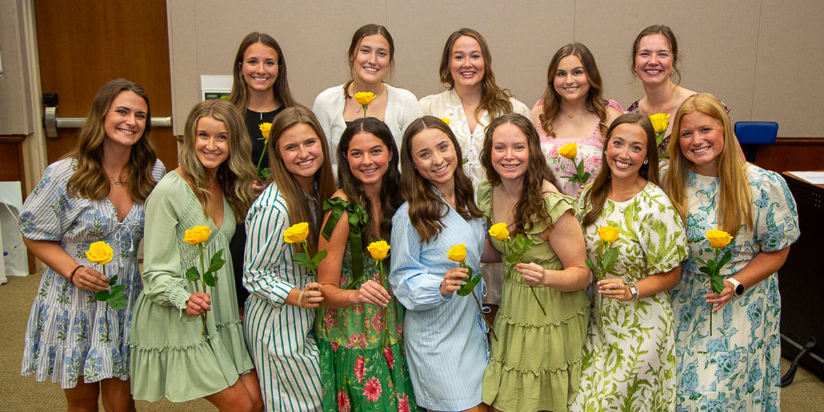 Group of Pi Theta Epsilon holding yellow roses
