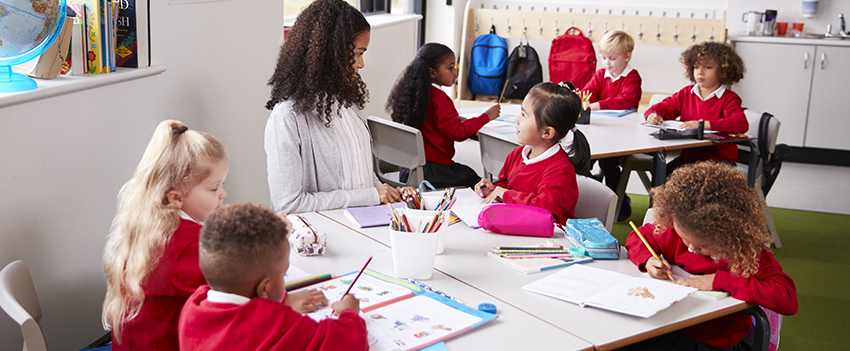 Teacher working with kids at tables in the classroom.