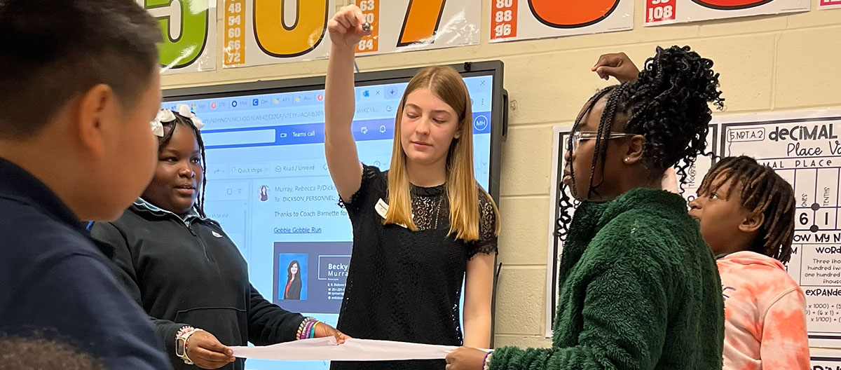 UTeach Student teacher working with students on a science experiment.