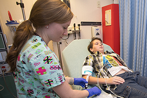 Nursing student working with patient laying in bed.