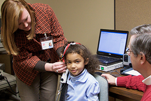 Student looking in little girl's ear.