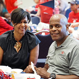 Two alumni members sitting at tailgate table.