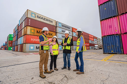  Dr. Peter Simonson, center, assistant professor in the Mitchell College of Business, collaborates with leadership at the Alabama Port Authority and APm Terminals to make sure coursework in supply chain logistics aligns with industry needs. He is here with two APM employees, both USA alumni, and a South Student intern.