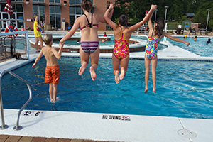 Kids jumping into Rec Center outdoor pool.