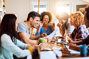 People sitting around table eating pizza.