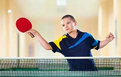 Young boy playing ping pong.