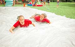 Camp counselors sliding on slip and slide.