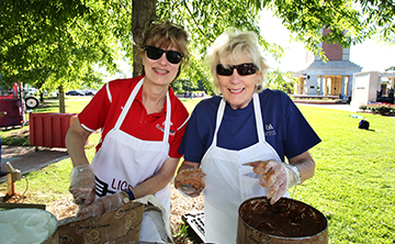 Two women helping with food at picnic.