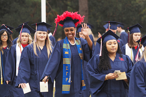 Students in cap and gowns walking to graduation.